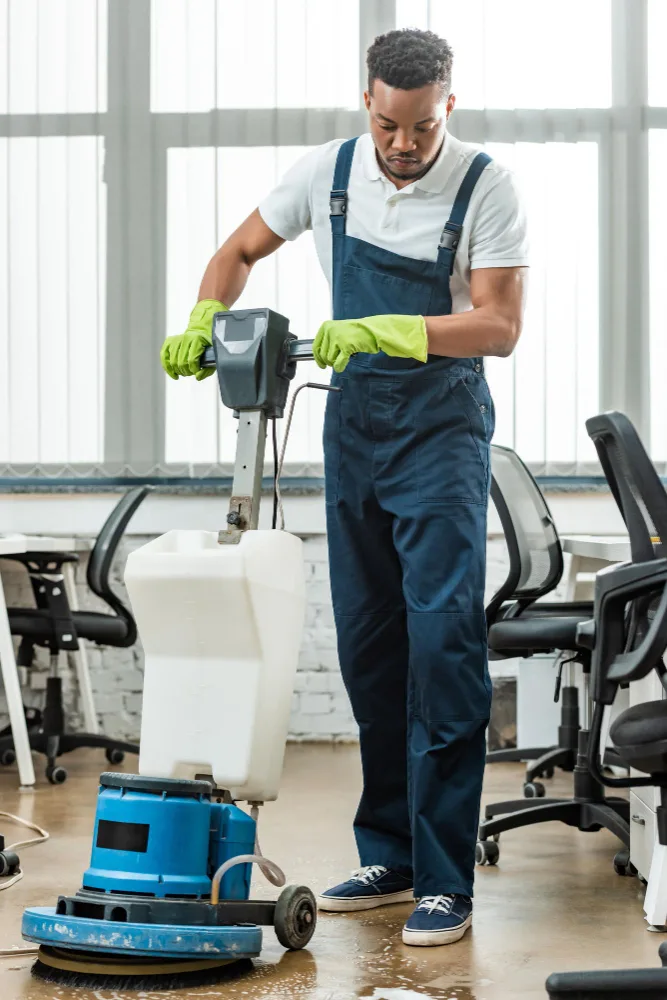 Reinigungskraft bedient eine Bodenmaschine im Büro